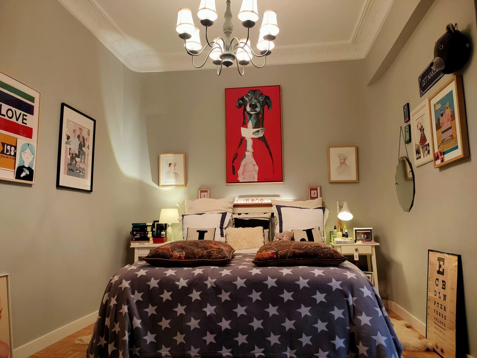 El dormitorio, sereno y elegante, está presidido por un galgo rojo pintado por Pedro Lindez. Los retratos personalizados y un espejo centenario completan el espacio con carácter íntimo.