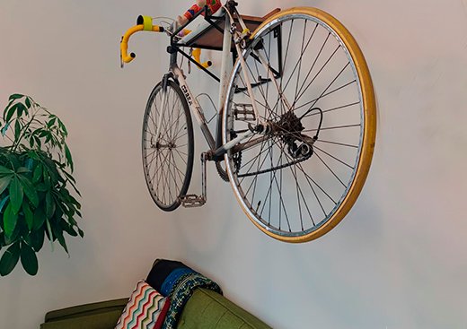 La bicicleta colgada sobre el sofá verde es un guiño a la vida diaria. Nada es pose: todo se habita y se disfruta.