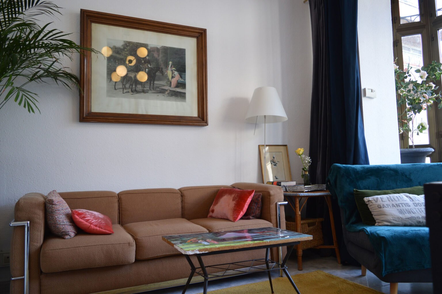 Salón vintage: sofá Le Corbusier, mesa de teselas japonesa, y luz filtrada por cortinas azules.