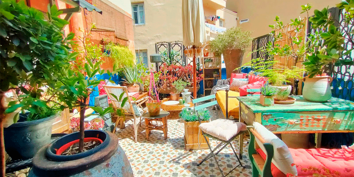 Vista general de la terraza: vegetación exuberante, muebles recuperados y color por todas partes.